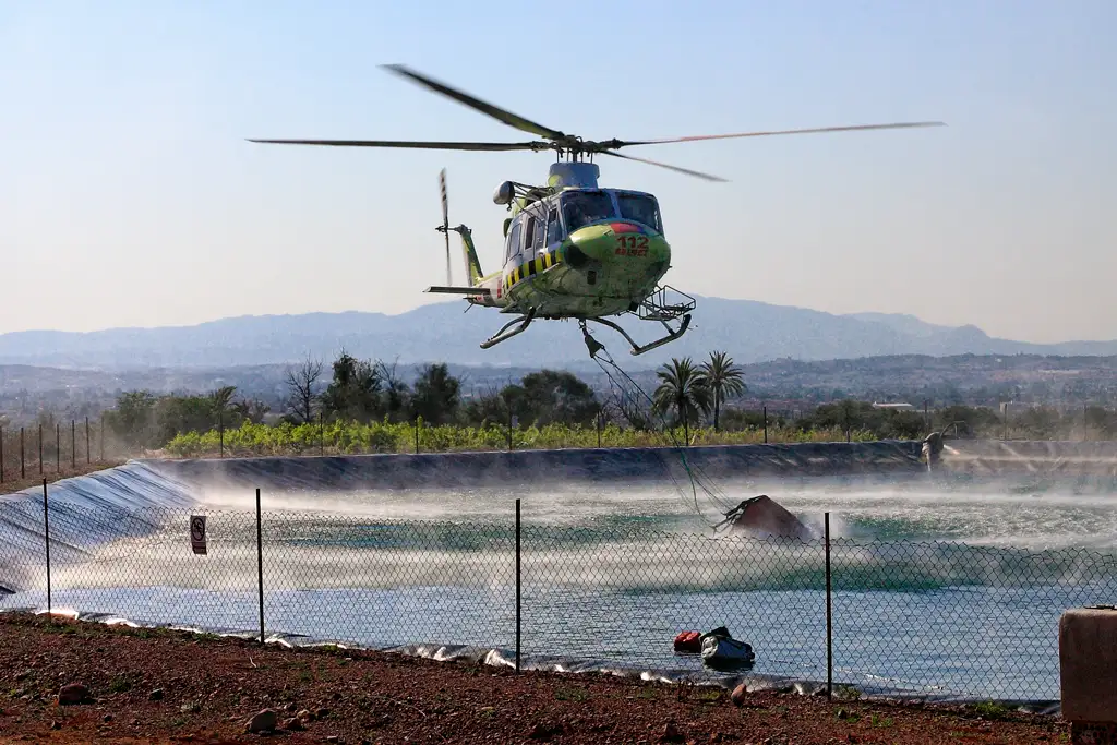 Helicóptero de bomberos cargando agua en su helibalde para extinguir un incendio forestal en el Parque Regional El Valle Helicóptero de bomberos cargando agua en su helibalde para extinguir un incendio forestal en el Parque Regional El Valle